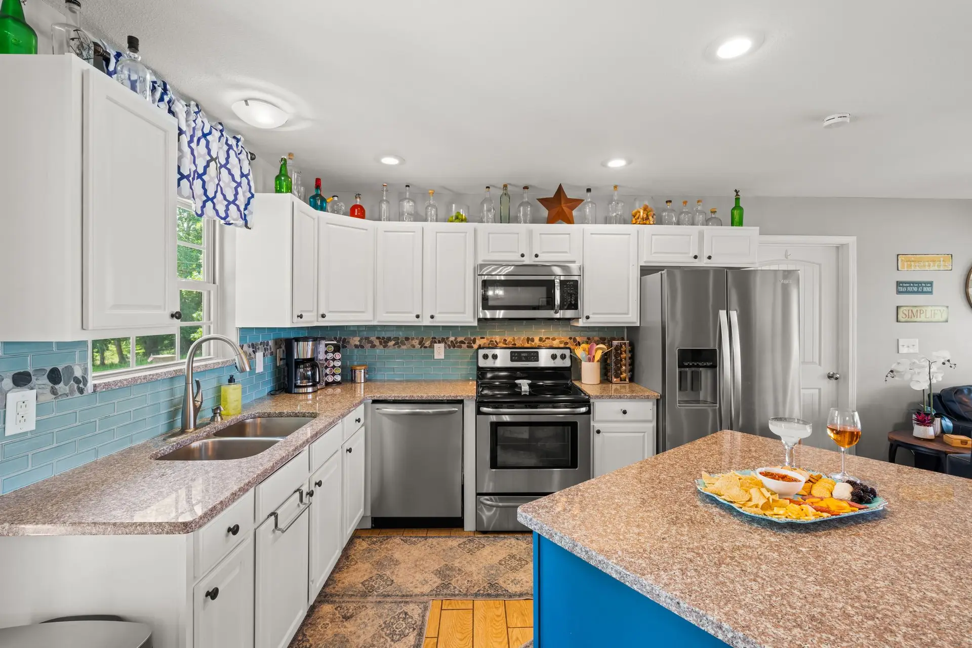 Kitchen with teal subway-tile backsplash, stainless range and granite island