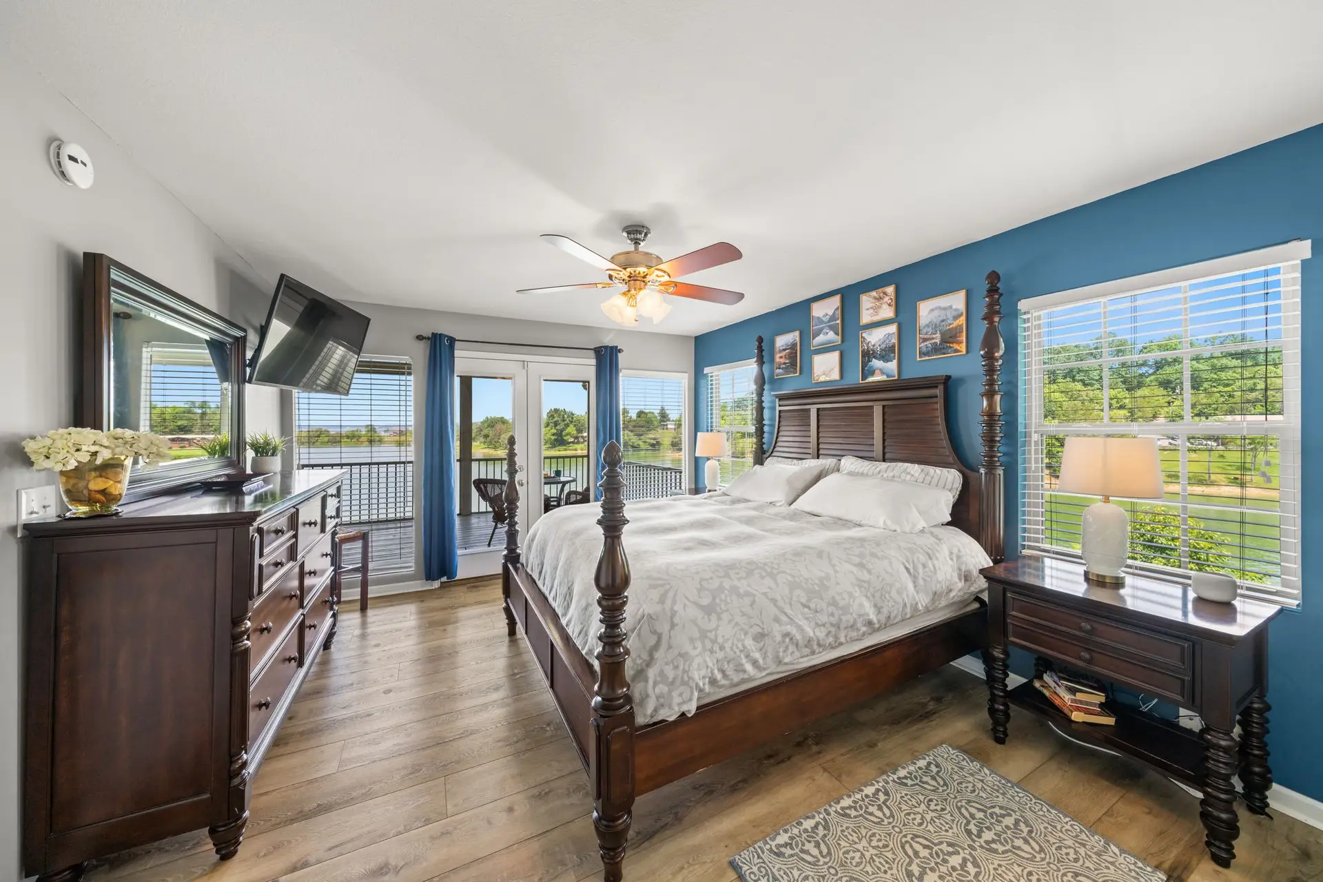 Main-level king bedroom with a four-poster bed against a deep blue accent wall and lake views