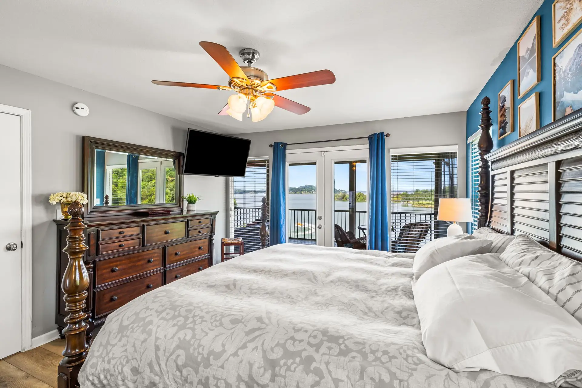 Main-level bedroom 1 with king bed, dresser, wall-mounted TV and French doors to the deck