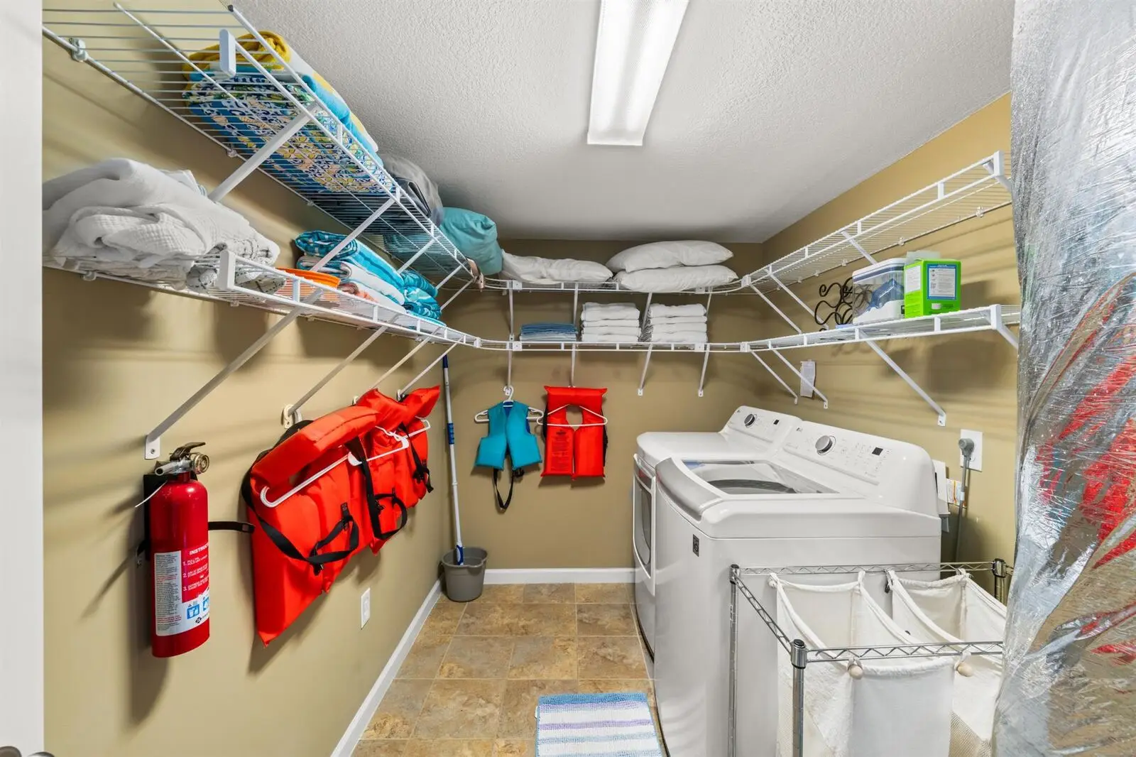 The laundry room with full-size washer and dryer, drying racks, and the house life jackets on the wall
