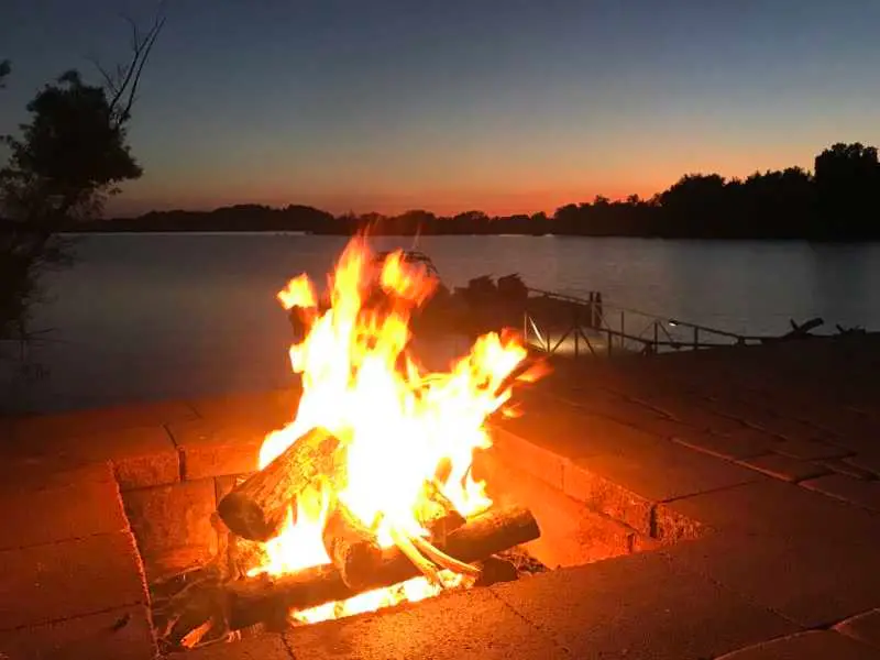 Lakeside fire pit glowing at dusk at Fort Sunsets