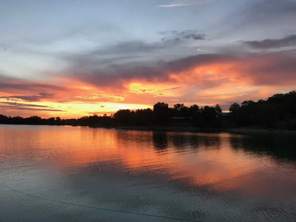 Vivid orange and pink sunset over Douglas Lake with brilliant colors reflected on the still water surface, tree-lined shoreline silhouetted against the glowing sky
