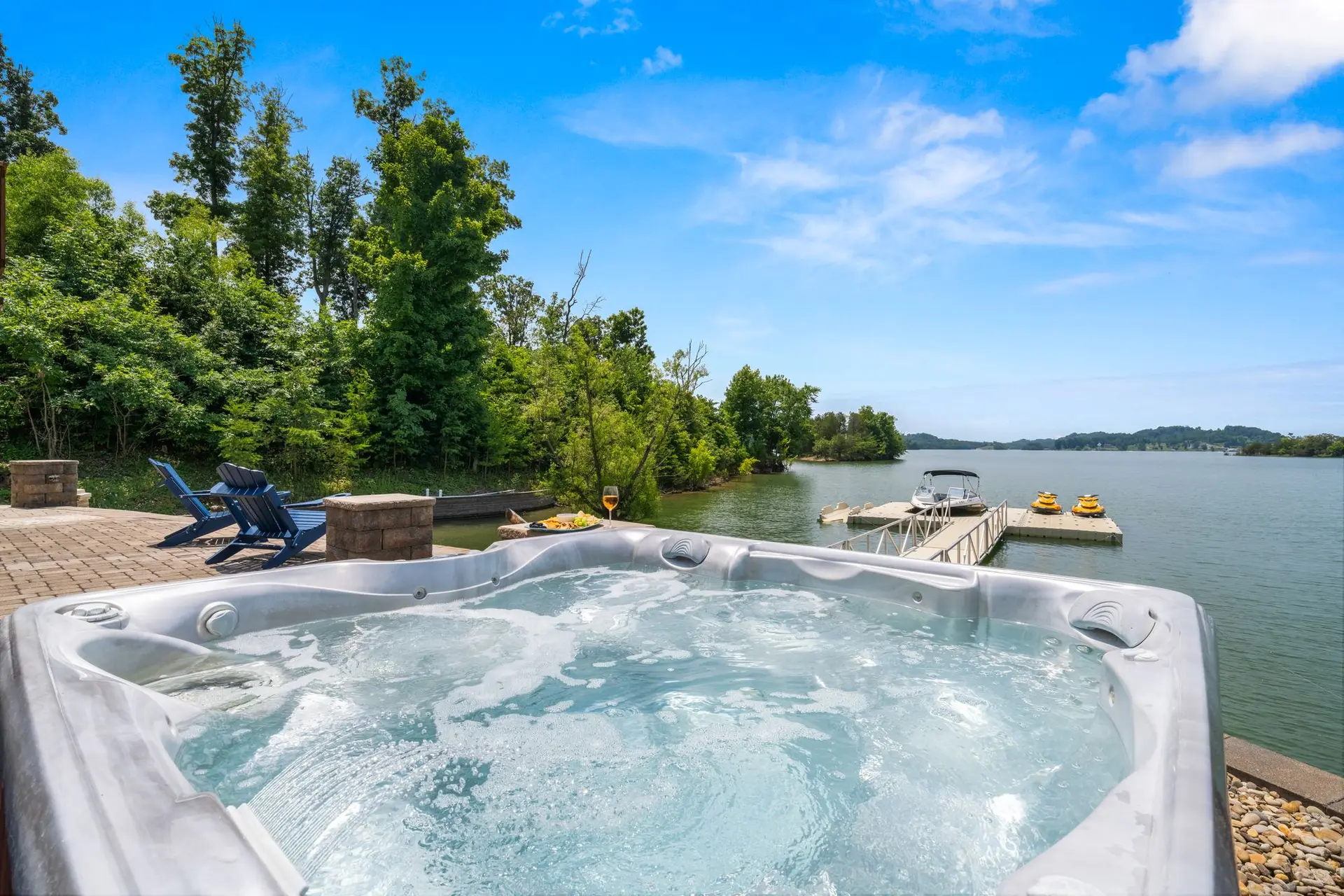 Bubbling hot tub looking straight out to the floating dock and Douglas Lake under a blue sky