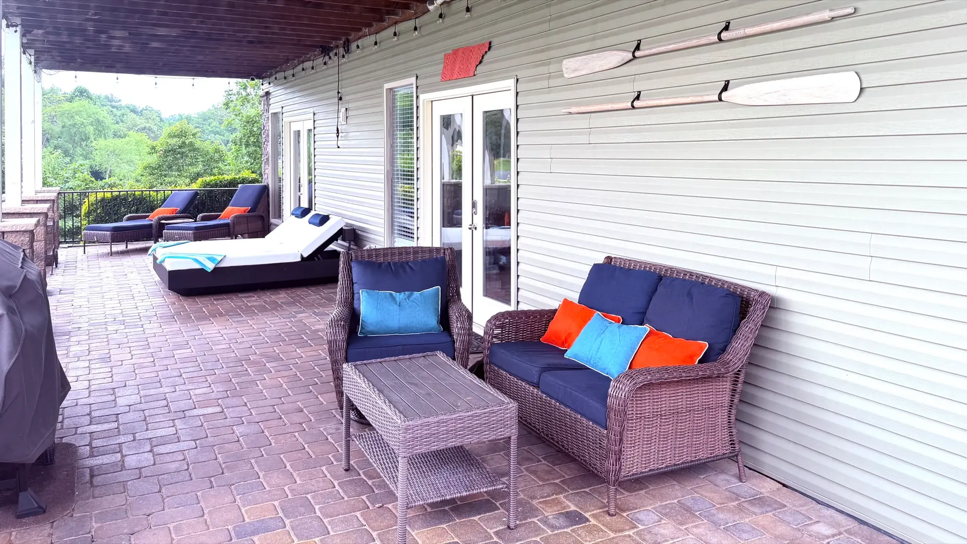 Wicker seating on the covered cobblestone patio with decorative oars on the wall