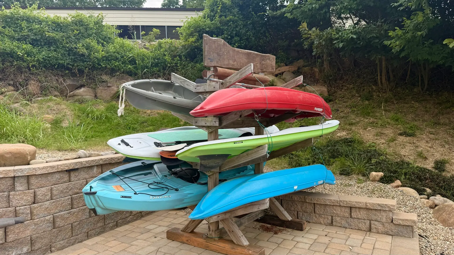 Close-up of the rack holding the full fleet — kayaks and stand up paddle boards ready to launch