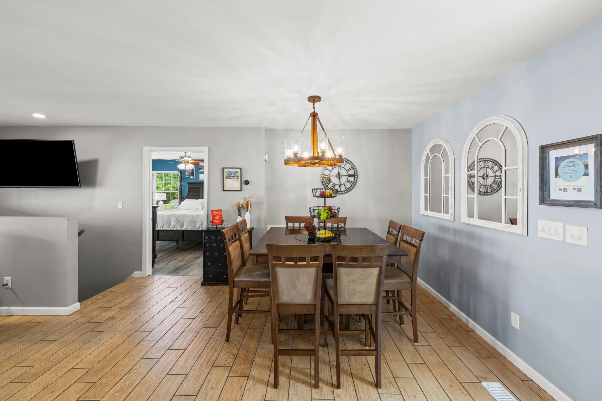 Dining table for eight under a rustic chandelier with arched mirrors on the wall