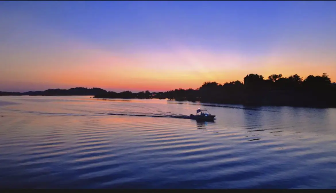A boat crossing the lake under a purple dusk sky
