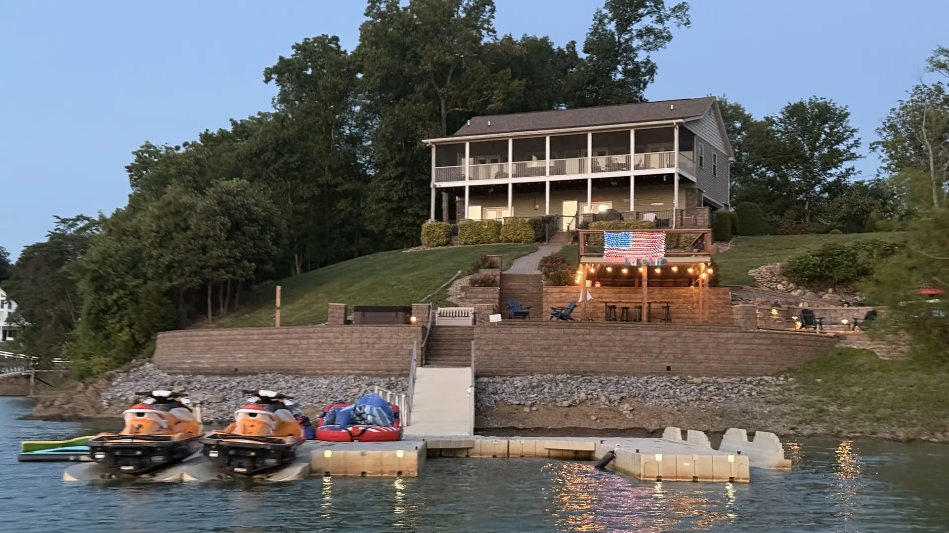 Fort Sunsets seen from the water at dusk with the American flag, lit hardscape and jet skis on the floating dock