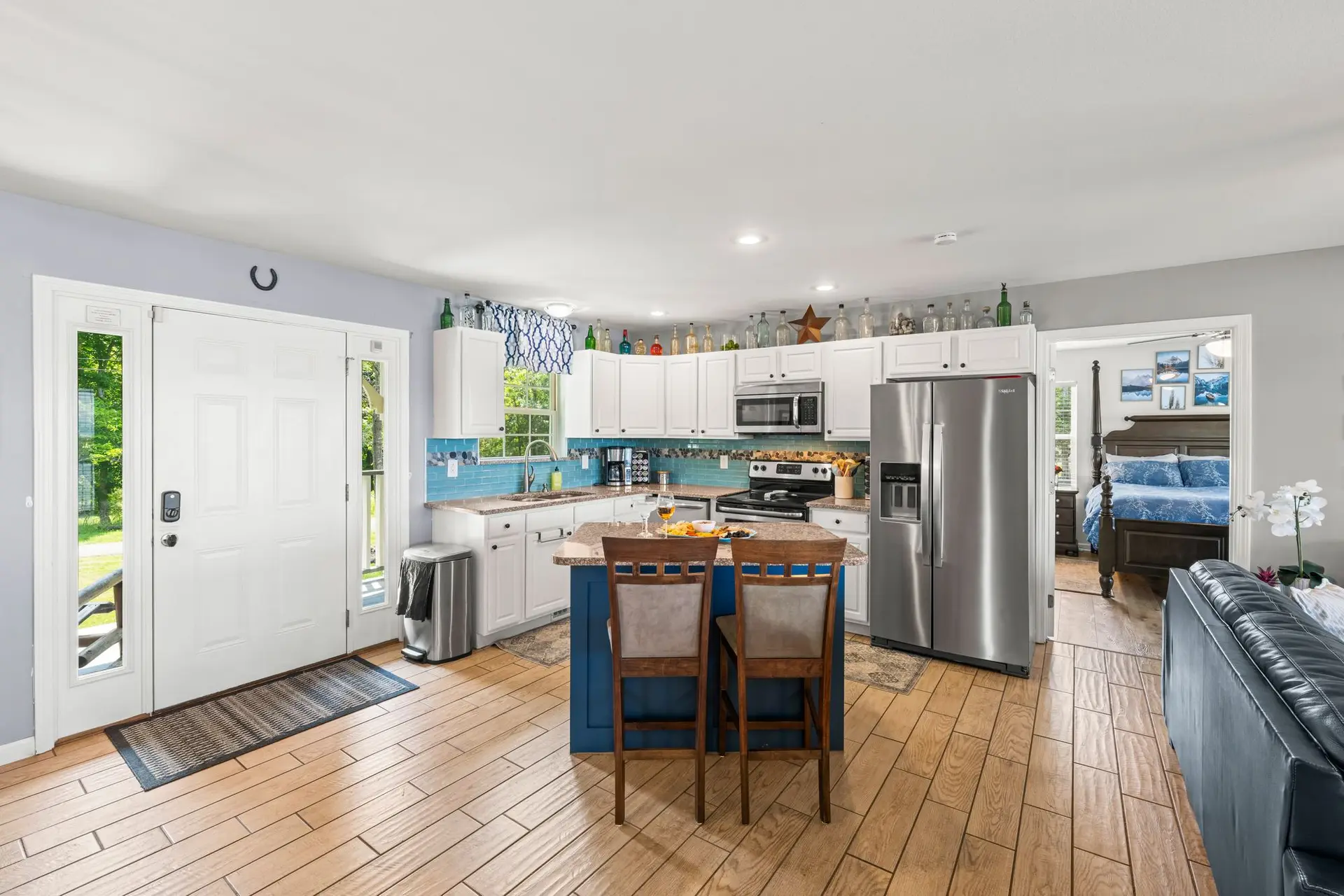 Wide view from the entry across the kitchen island and stainless appliances into the living room