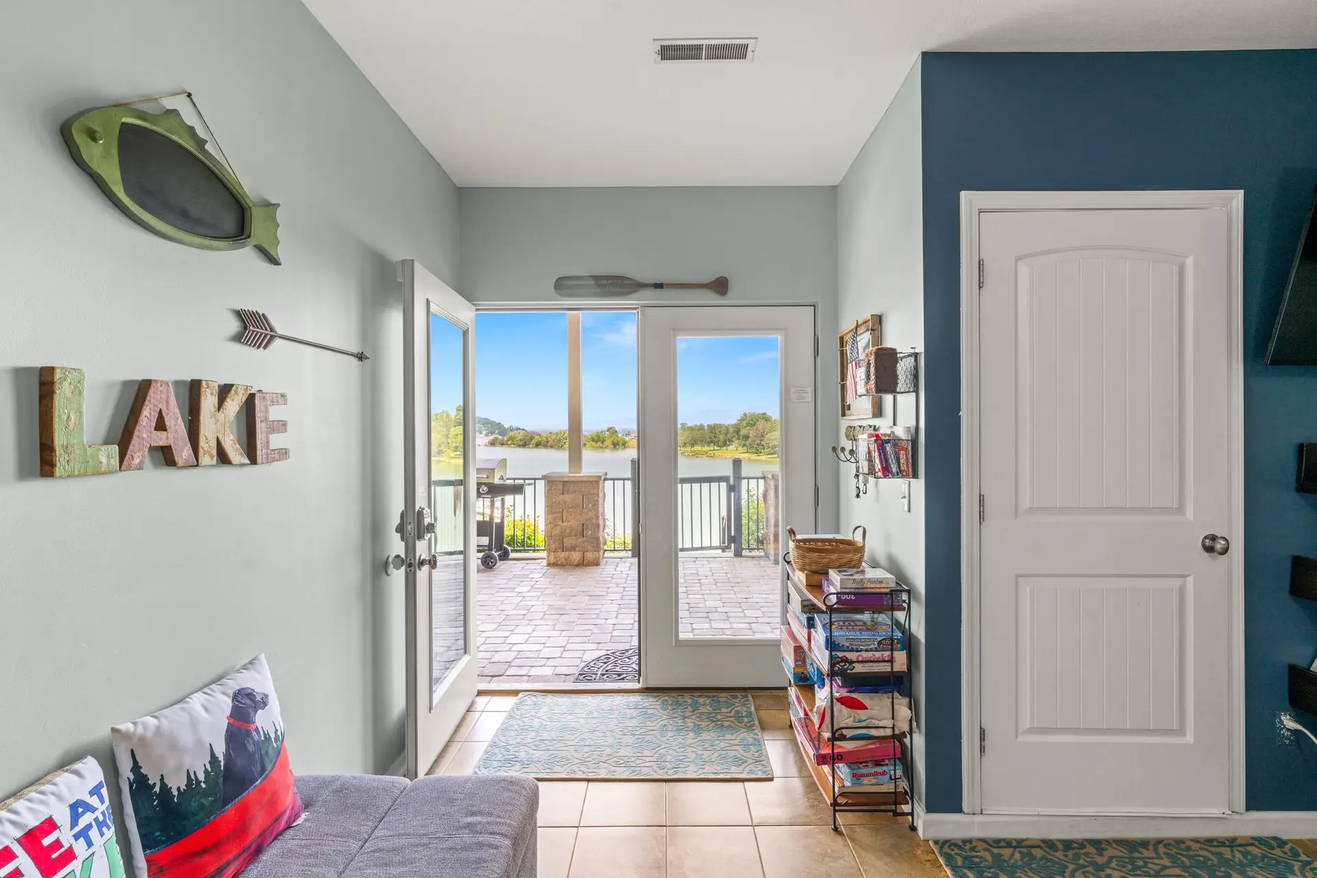 Rec room entry with LAKE letters, futon and doors out to the lower patio and lake