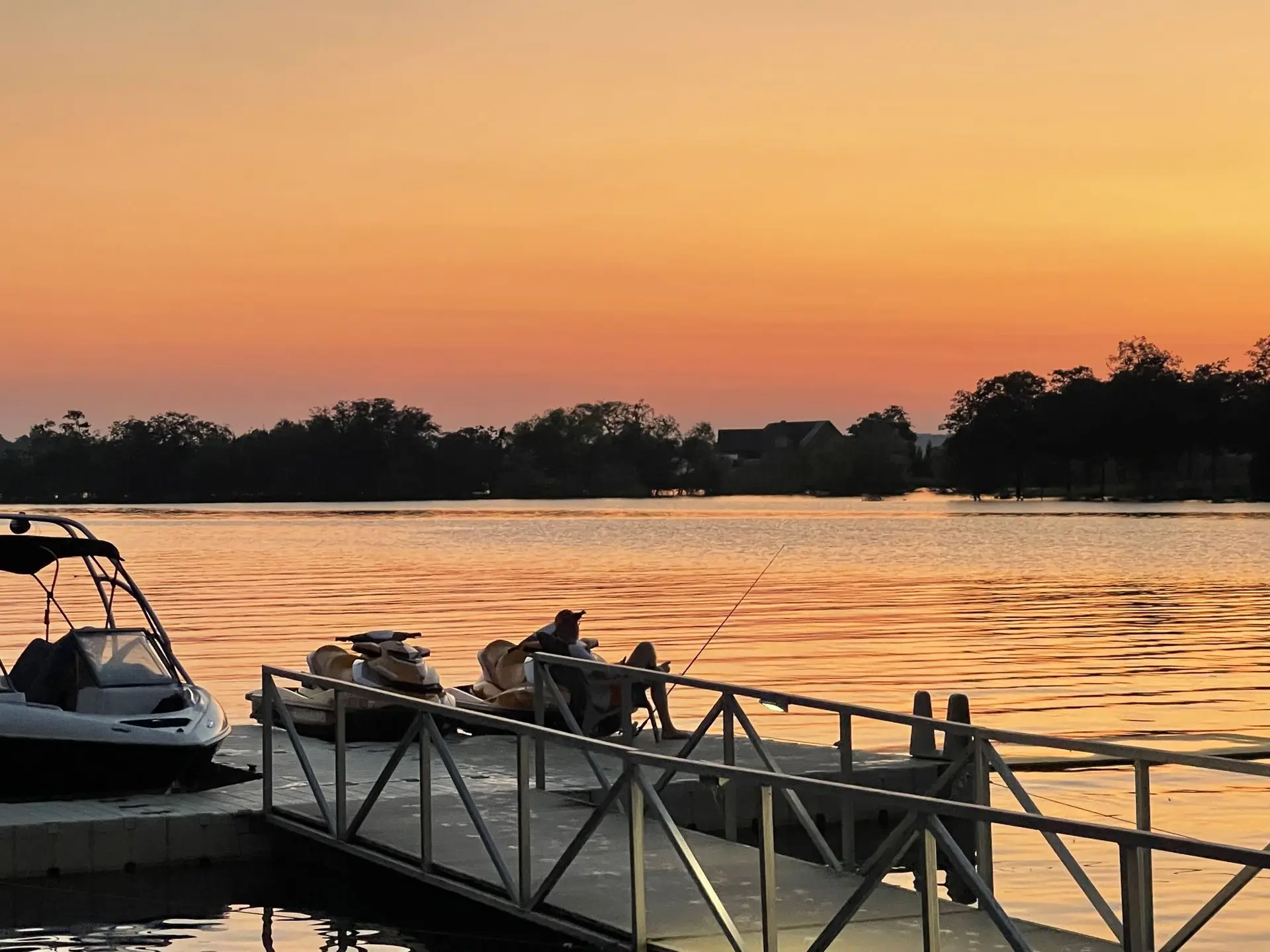 Boat and jet skis on the floating dock in golden sunset light